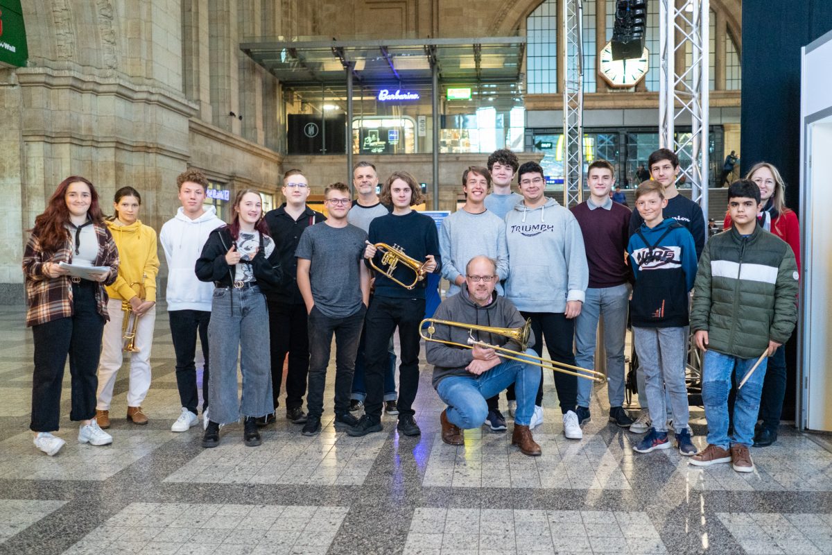 Gruppenfoto, Mitglieder der Junior Bigband stehen in der Eingangshalle des Hauptbahnhofes mit ihren Instrumenten