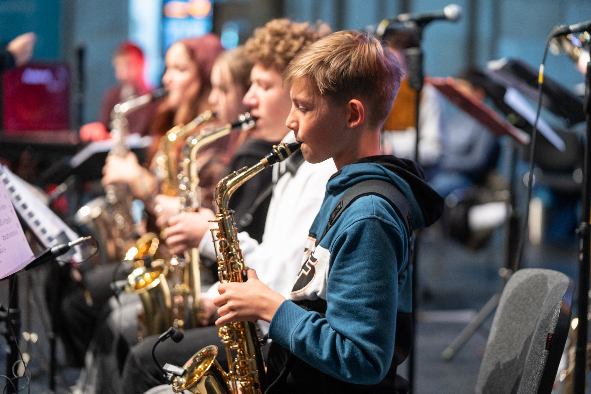 Mitglieder der Junior Bigband bei der Feier "25 Jahre Promenaden im Hauptbahnhof", im Vordergrund sitzen junge Musiker/-innen, die Saxophon spielen